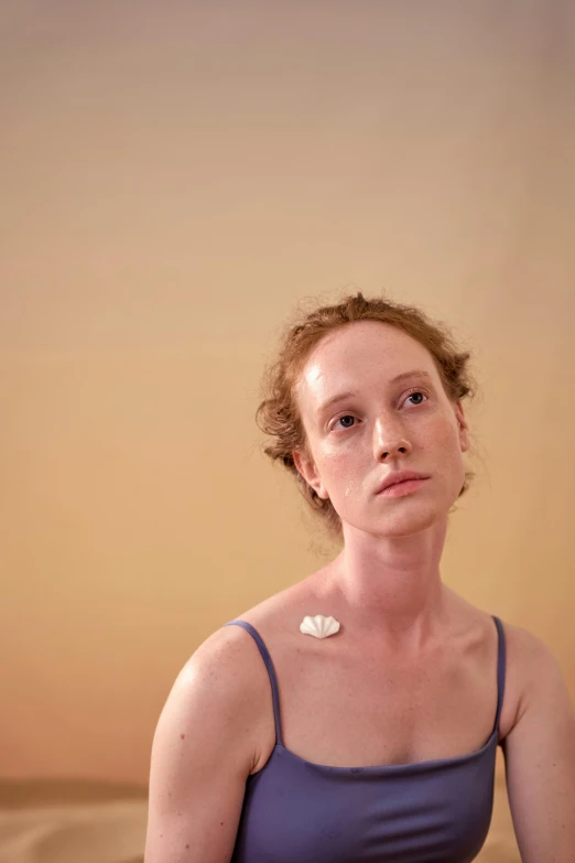 a woman sitting on a bed with a remote in her hand, an album cover, by Elizabeth Polunin, hyperrealism, a plaster on her cheek, freckled pale skin, photograph taken in 2 0 2 0, attractive neck