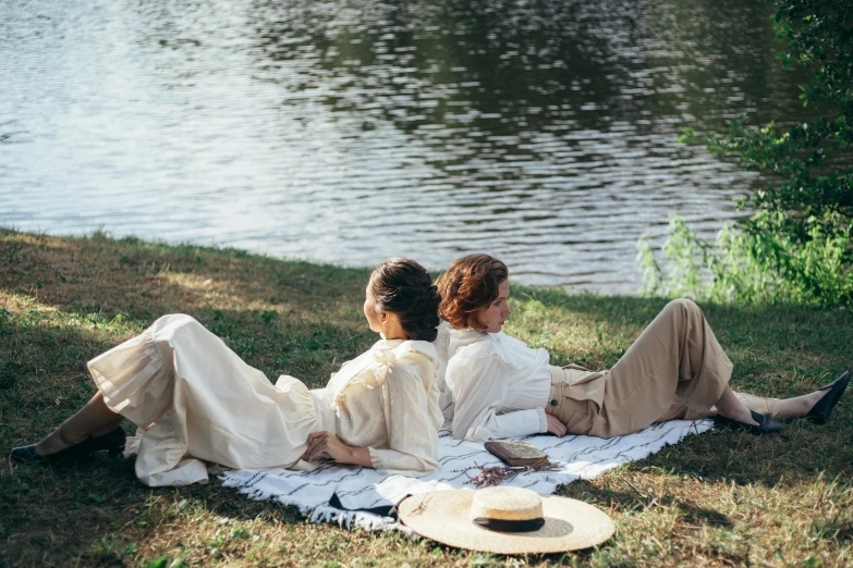 a couple of women sitting on top of a grass covered field, inspired by Konstantin Somov, trending on unsplash, renaissance, in a park and next to a lake, dirty linen robes, people outside eating meals, sydney park