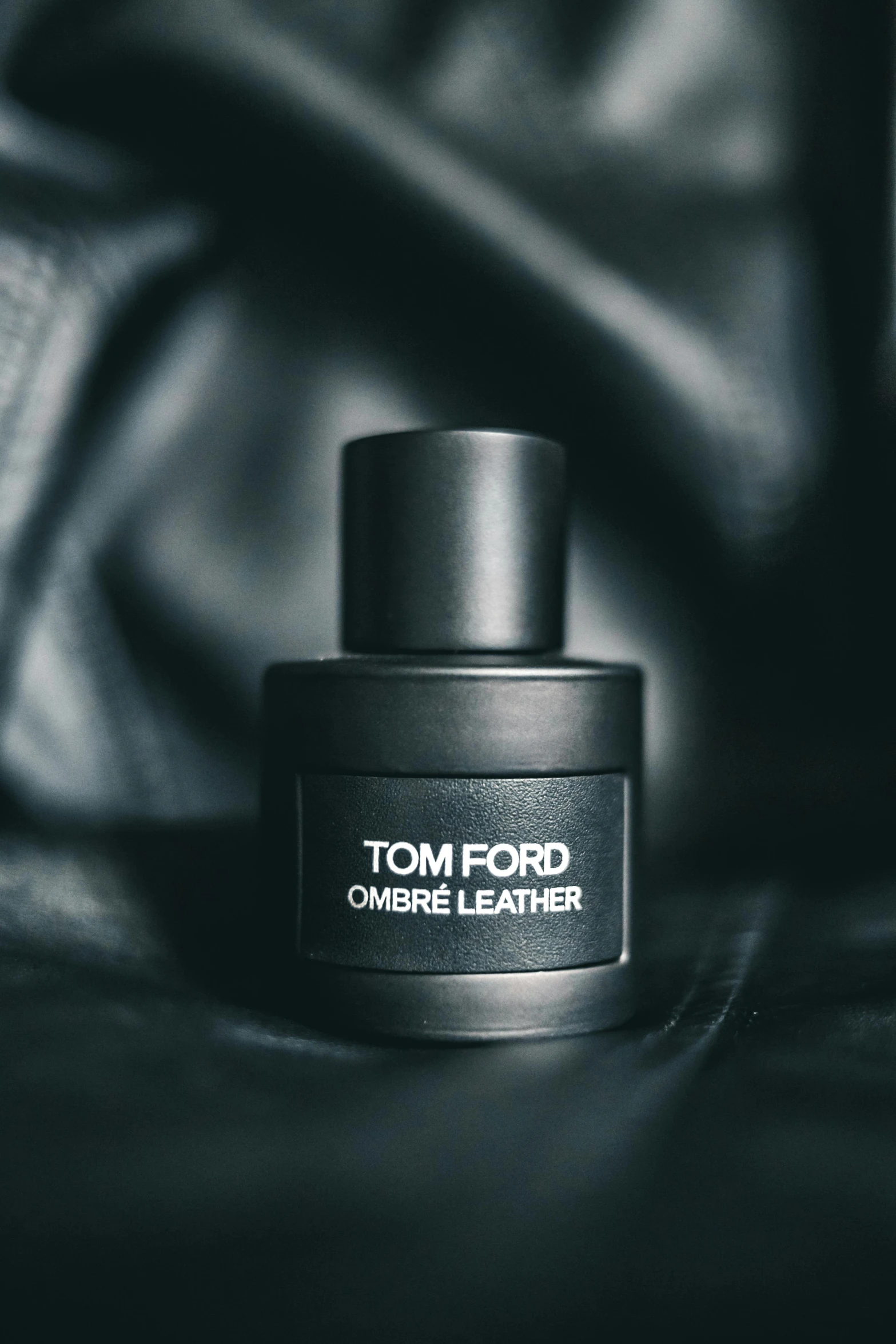 a bottle of tom ford cologne on a black leather surface, by Thomas Fogarty, reddit, tonalism, ombre, ( ( theatrical ) ), leather boots, thumbnail