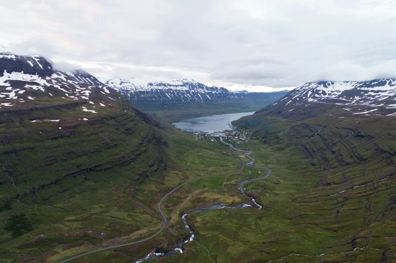 a river running through a lush green valley, by Daren Bader, pexels contest winner, hurufiyya, snowy fjord, aerial footage, balaskas, with mountains in background