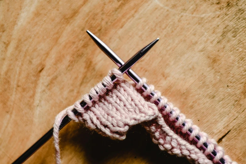 a pair of knitting needles sitting on top of a wooden table, trending on pexels, pink, wielding a crowbar, mid - action, textile