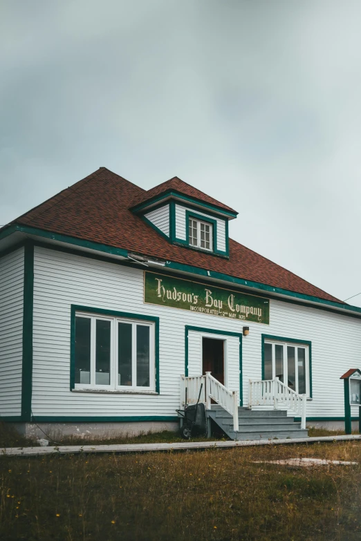 a white and green building sitting on top of a grass covered field, by Robbie Trevino, fishing village, francois legault, shop front, 90s photo