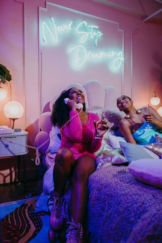 a group of people sitting on top of a bed, inspired by David LaChapelle, trending on pexels, maximalism, ( ( dark skin ) ), two women, sitting in a lounge, pink lighting