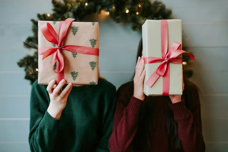 two women holding presents in front of a christmas tree, by Alice Mason, pexels contest winner, square, hands pressed together in bow, a handsome, gif