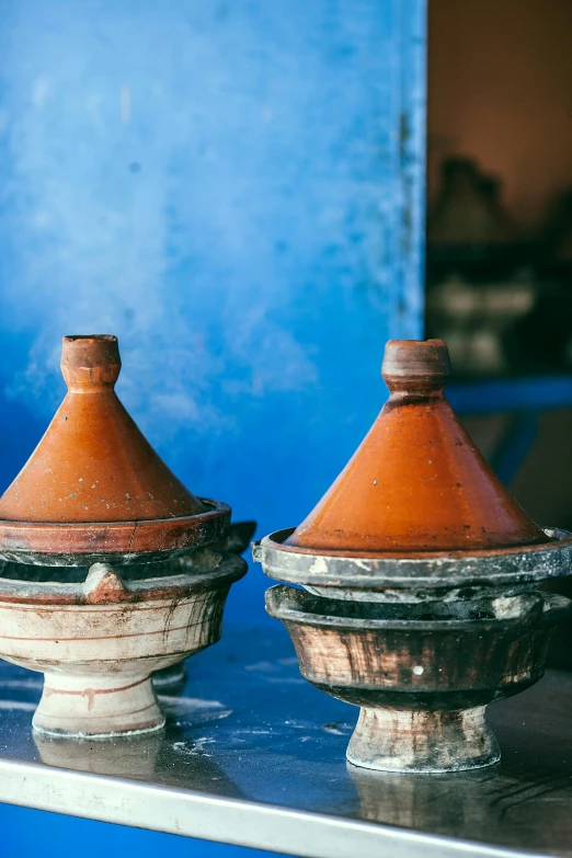 a couple of pots sitting on top of a counter, inspired by Alberto Morrocco, trending on unsplash, renaissance, whirling blue smoke, moroccan mosque, cone shaped, medium shot close up