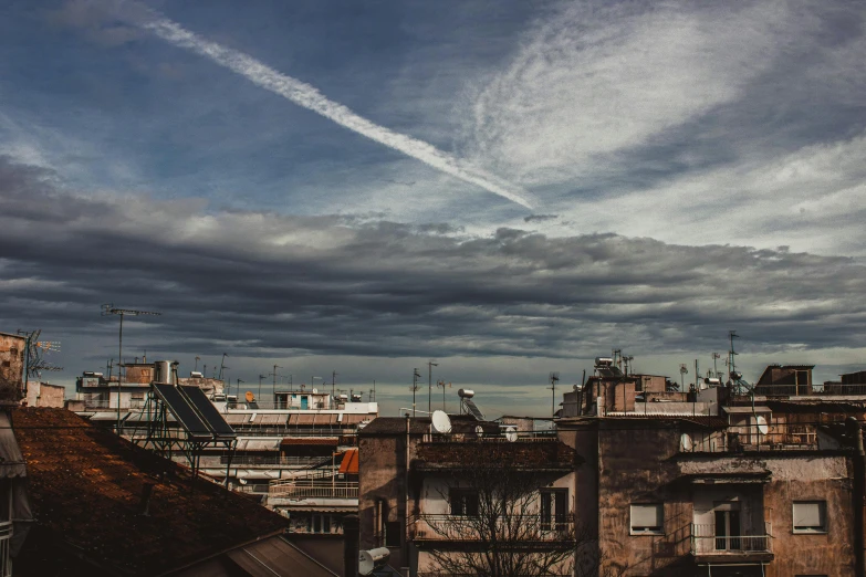 a group of buildings sitting next to each other under a cloudy sky, by Alessandro Allori, pexels contest winner, contrails, urban view in the distance, slide show, late afternoon