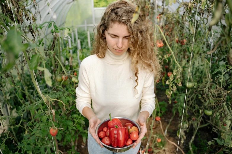 a woman holding a bowl of strawberries in a greenhouse, by Emma Andijewska, pexels contest winner, renaissance, red sweater and gray pants, pepper, paprika, portrait of tall