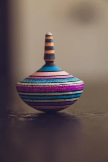 a wooden toy sitting on top of a table, by Sam Havadtoy, unsplash, kinetic art, some purple and blue, vase, striped, ornamented
