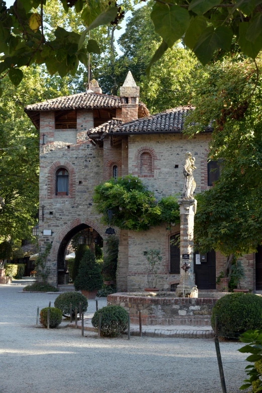 a stone building surrounded by trees and bushes, inspired by Serafino De Tivoli, romanesque, village square, entrance, tower, restaurant