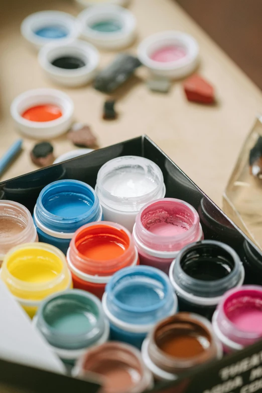 a box of paint sitting on top of a table, a watercolor painting, by Elsie Few, trending on pexels, color gel, bottles covered in wax, car paint, diverse colors
