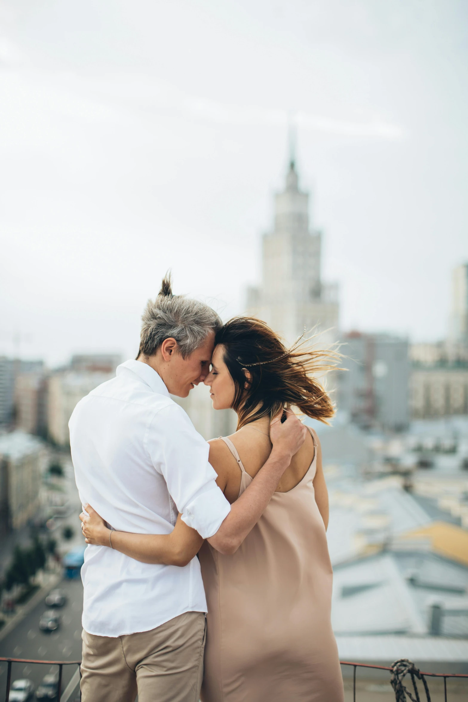 a man and woman standing next to each other on a balcony, by Adam Marczyński, pexels contest winner, skyline in back, loving embrace, ukrainian, plain background