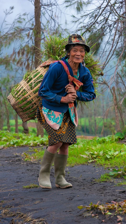 a woman walking down a path with a basket on her back, by Robert Medley, pexels contest winner, sumatraism, tall farmer, looking happy, dressed as a scavenger, thumbnail