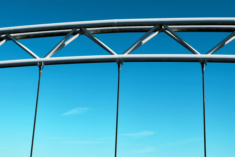 a group of people riding on top of a bridge, a 3D render, inspired by Richard Wilson, metal framed portal, clear blue skies, neck zoomed in, swings