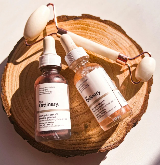 a couple of bottles of liquid sitting on top of a wooden slice, by Julia Pishtar, skincare, with godray, ordinary, display