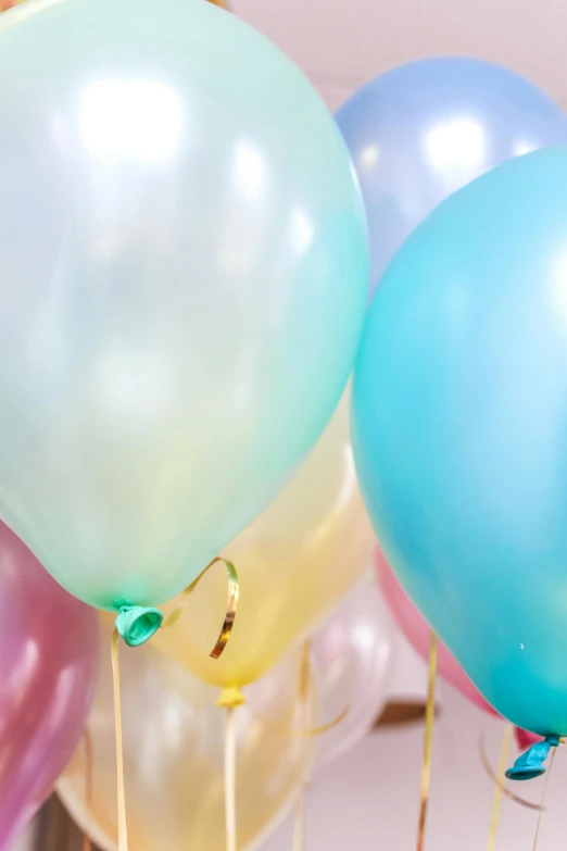 a bunch of balloons sitting on top of a table, upclose, pastelcolours, pearlescent, medium - shot