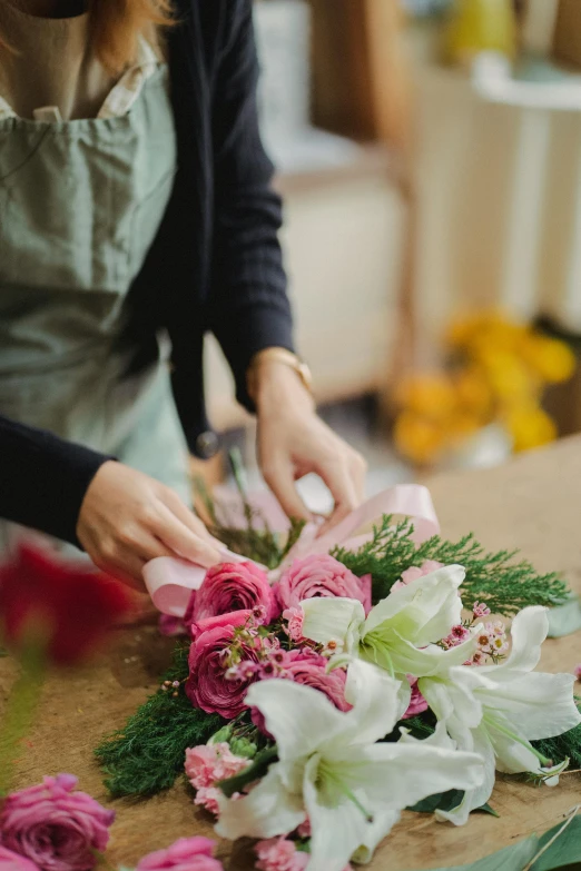 a woman is making a bouquet of flowers, by Elsie Few, trending on unsplash, slick elegant design, flower shop scene, ribbons and flowers, meticulous details