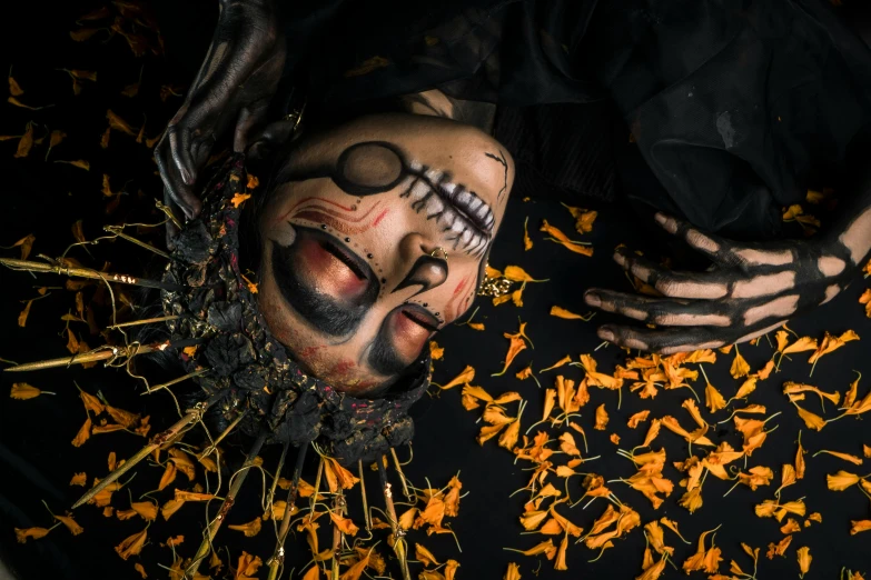 a close up of a person laying on a bed of flowers, a portrait, inspired by Taro Yamamoto, pexels contest winner, vanitas, creepy masked marionette puppet, orange and yellow costume, dark and intricate, top - down view