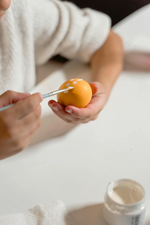 a woman is peeling an orange with a pair of scissors, a photorealistic painting, inspired by Michaelangelo, pexels, translucent eggs, square, easter, on