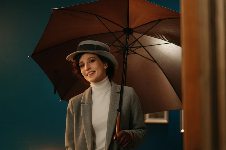 a woman in a hat and coat holding an umbrella, pexels contest winner, meet the actor behind the scenes, animation still, indoor scene, brown