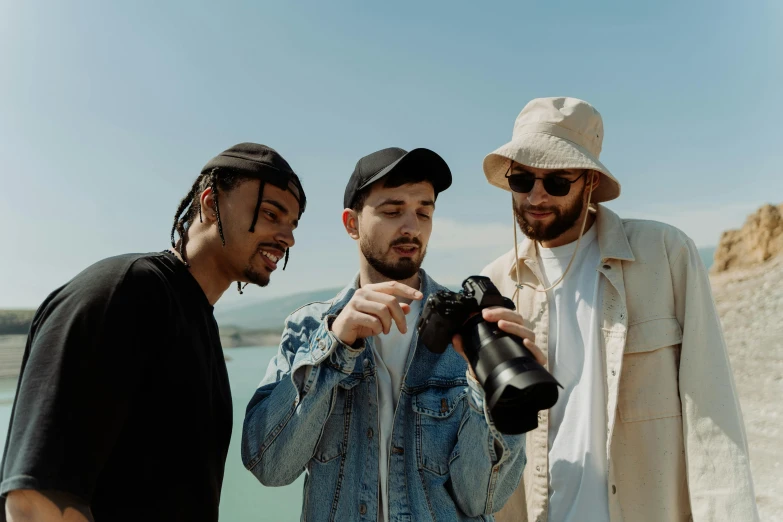 three men standing next to each other near a body of water, a picture, pexels contest winner, visual art, performing a music video, holding a camera, high quality product image”, headshot