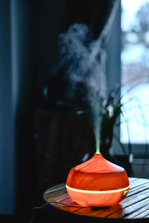 a red vase sitting on top of a table next to a window, whirling smoke radiant colors, spa, cedar, front lit