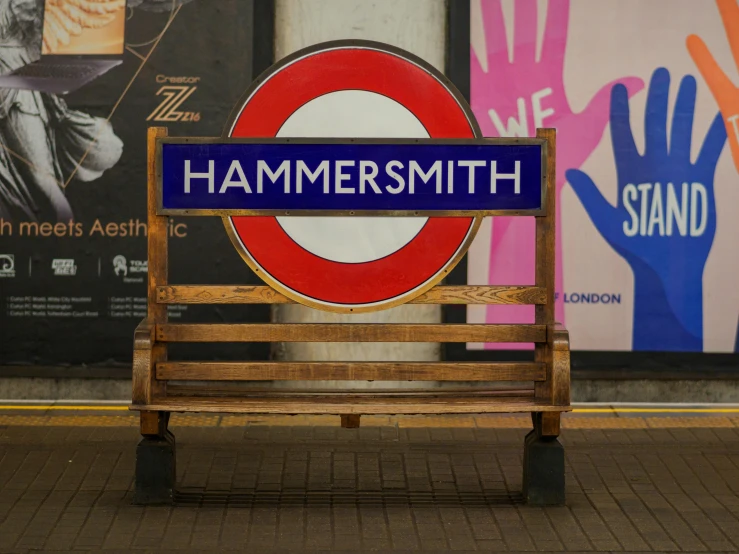 a wooden bench sitting in front of a sign, an album cover, inspired by Ian Hamilton Finlay, trending on unsplash, mannerism, london underground tube station, hammer's slammers, odeith, hardmesh