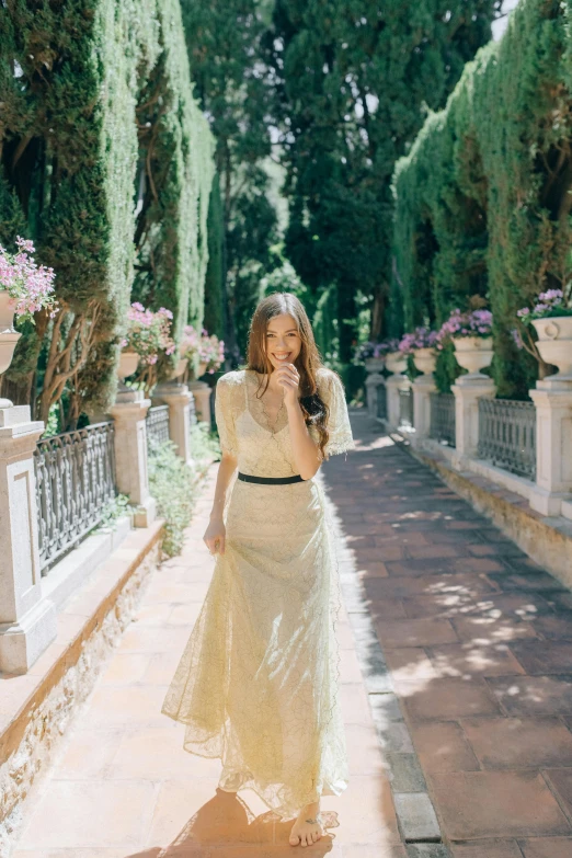 a woman in a white dress walking down a path, inspired by Luis Paret y Alcazar, unsplash, renaissance, at the terrace, lush garden surroundings, formal wear, hailee steinfeld