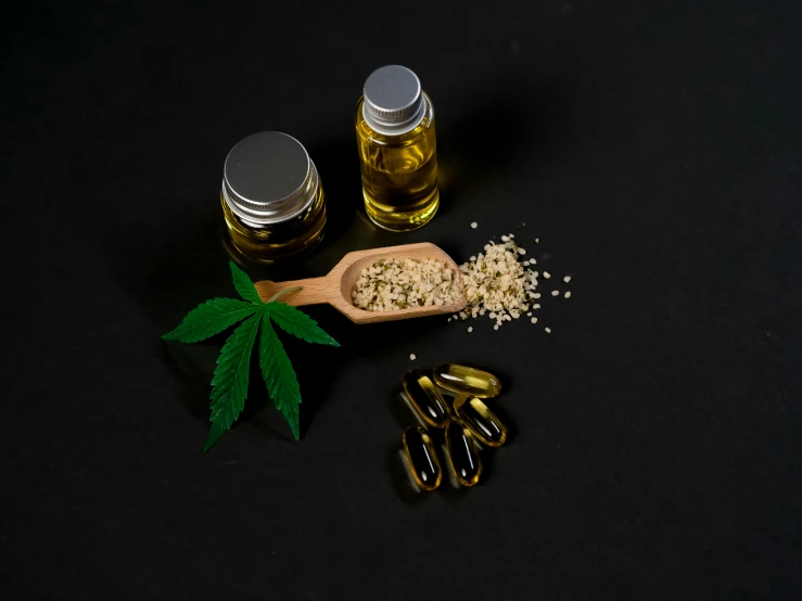 a wooden spoon sitting on top of a black table, vials, hemp, high-quality photo, ad image