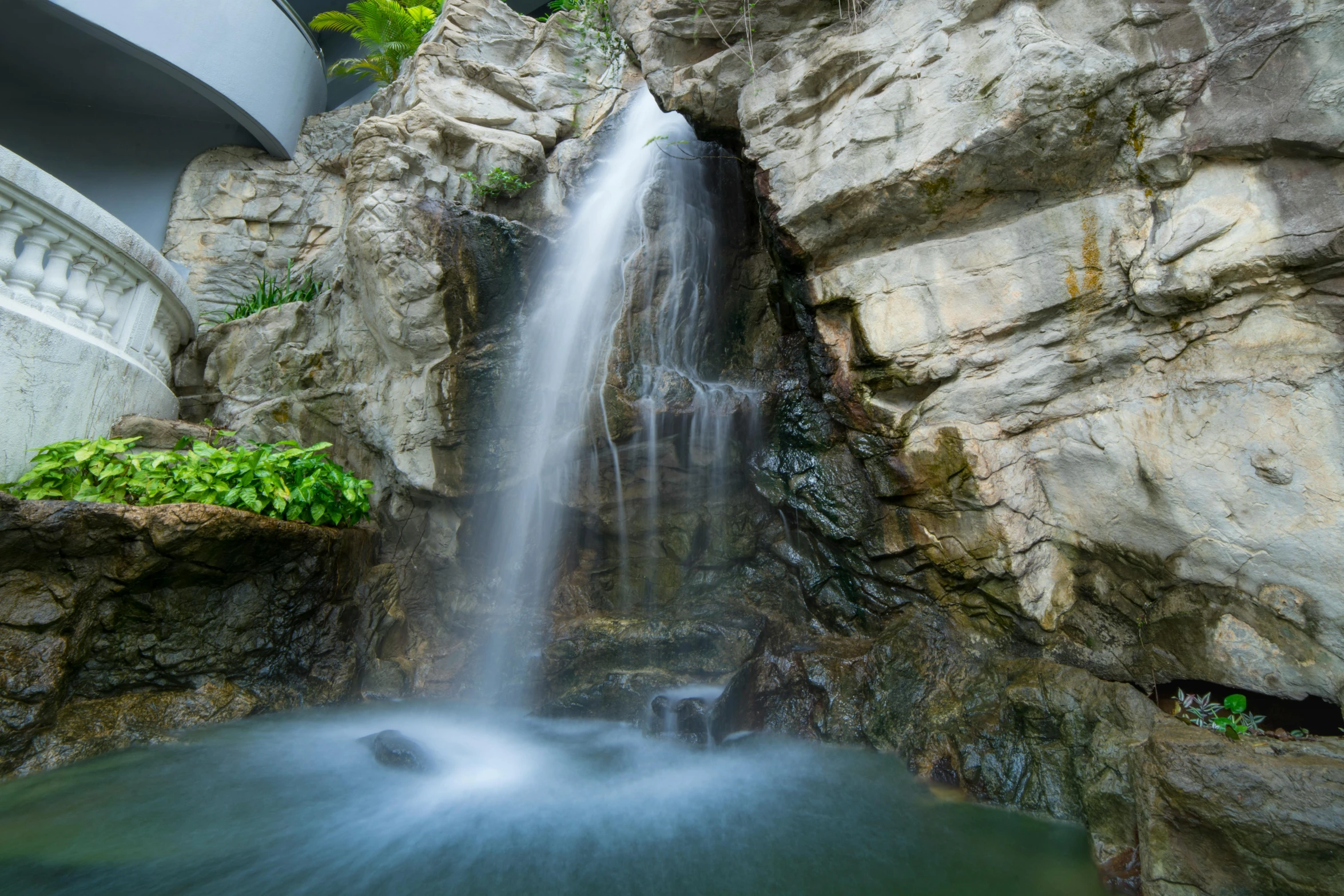 a waterfall cascades into a pool of water, by Reuben Tam, unsplash, okinawa churaumi aquarium, palm springs, taken in the early 2020s, paradise garden massage