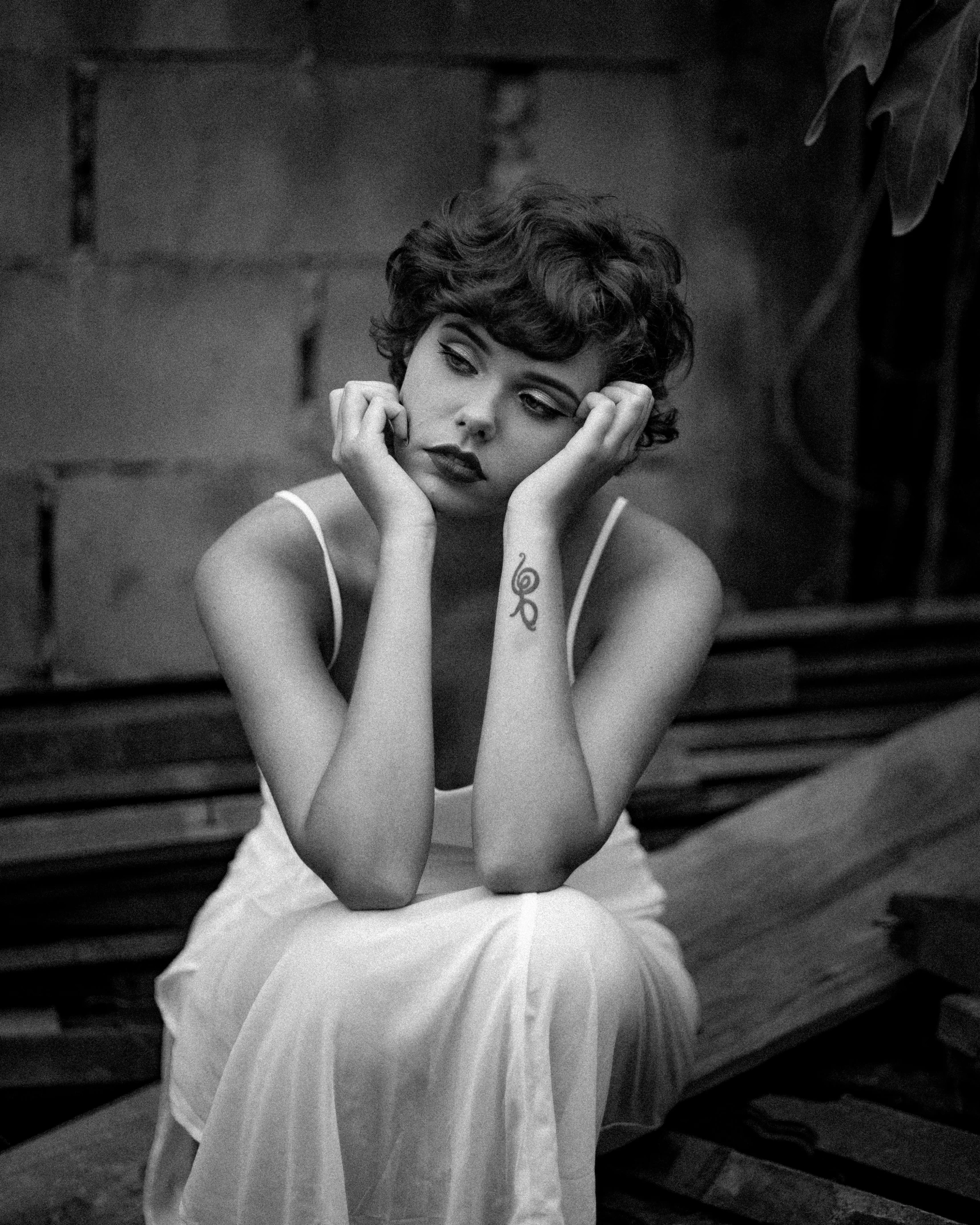 a black and white photo of a woman sitting on a bench, inspired by irakli nadar, curly pixie cut hair, girl with a pearl earringl, solemn gesture, ffffound