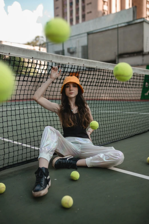 a woman sitting on top of a tennis court holding a racquet, an album cover, inspired by Ion Andreescu, trending on pexels, wearing a baseball cap, 5 0 0 px models, orange neon, at a fashion shoot