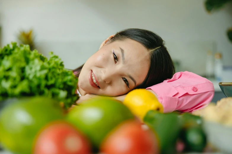 a woman laying on top of a counter next to a pile of fruit and vegetables, avatar image, darren quach, bashful expression, profile image