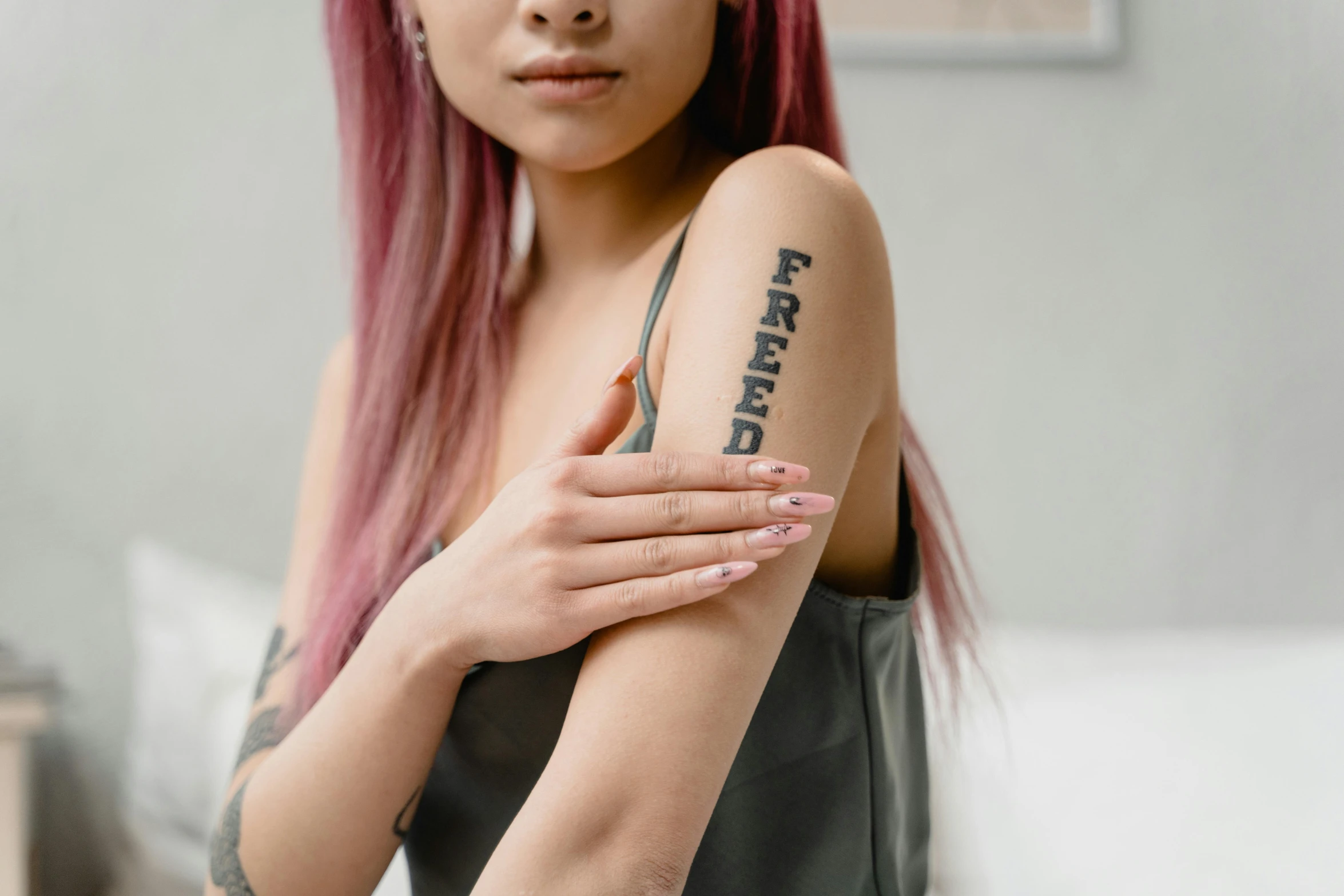 a woman with a tattoo on her arm, trending on pexels, wearing a tanktop, rated t for teen, asian female, queer woman