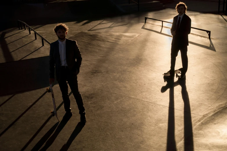 a couple of men standing next to each other on a skateboard, an album cover, by Niko Henrichon, pexels contest winner, portrait casting long shadows, in a suit, ( ( theatrical ) ), set at night