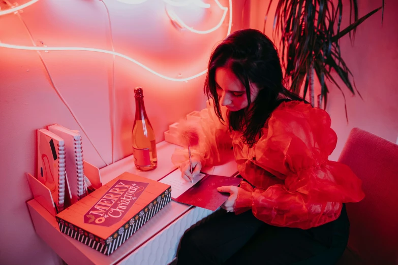 a woman sitting at a table in front of a neon sign, an album cover, pexels contest winner, red ballpoint pen, signing autographs, charli bowater and artgeem, reading the book about love