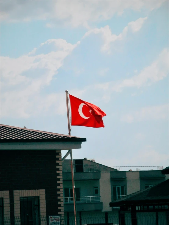 a turkish flag flying on top of a building, profile image, during the day, day time, in the distance