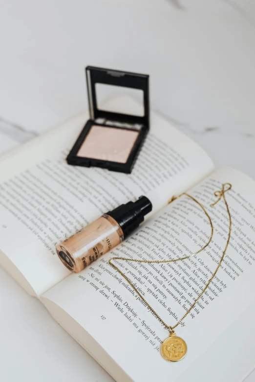 an open book sitting on top of a table, gold eyeshadow, necklace on display, perfect natural skin tones, glowing oil