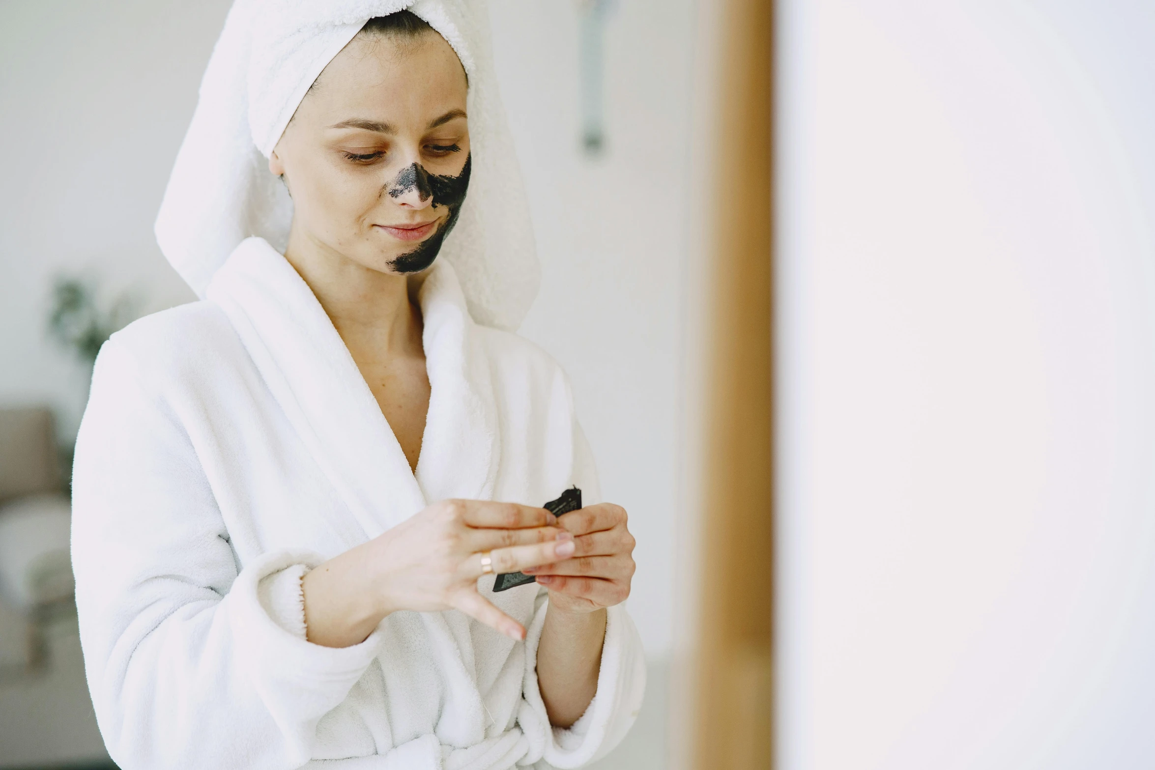 a woman in a bathrobe looking at her cell phone, trending on pexels, antipodeans, black mask, face painting, manuka, with grey skin