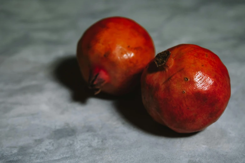 a close up of two pomegranates on a table, trending on pexels, background image, beets, medium format, grey