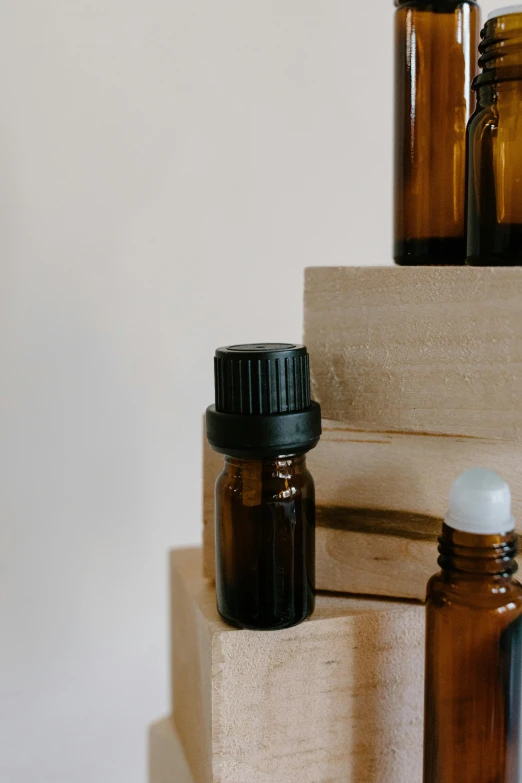 a stack of bottles sitting on top of a wooden block, by Robbie Trevino, trending on pexels, medical labels, brown, oud, oil