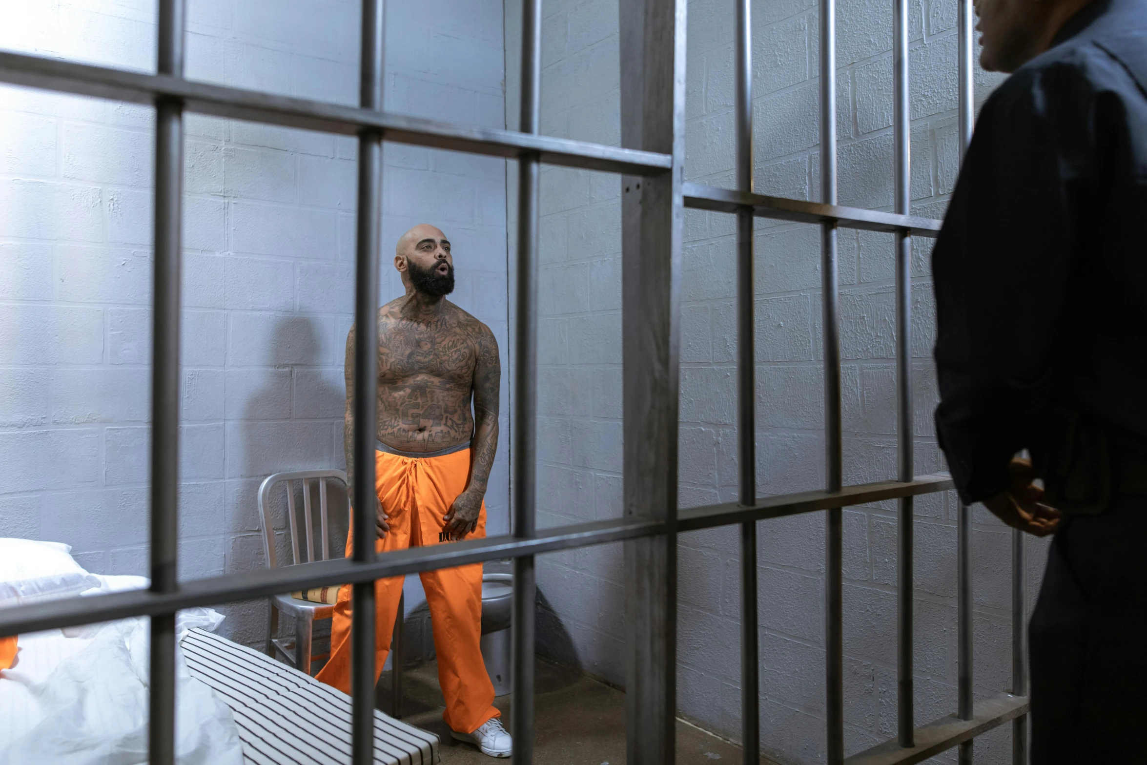 a man standing in a jail cell next to a bed, tattooed, on set, george floyd, mc ride