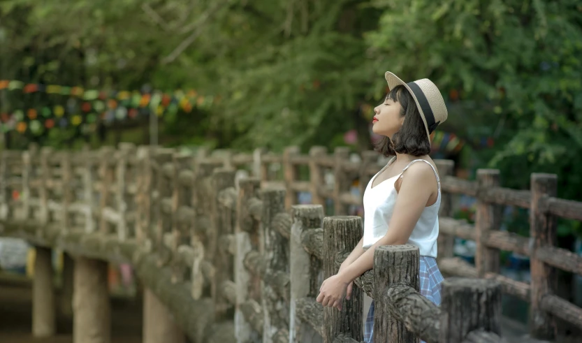 a woman standing on top of a wooden bridge, inspired by Ruth Jên, pexels contest winner, looking off to the side, caracter with brown hat, las pozas, asian girl