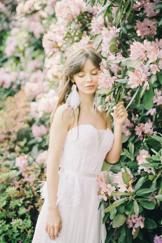 a woman standing in front of a bush of flowers, inspired by Oleg Oprisco, unsplash, romanticism, dressed in a beautiful white, feathers ) wet, wedding, 8 k )