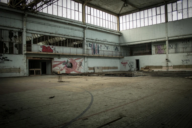 a man riding a skateboard on top of a cement floor, a portrait, inspired by Elsa Bleda, pexels contest winner, graffiti, vast empty hall, basketball court, ruins around, ((rust))