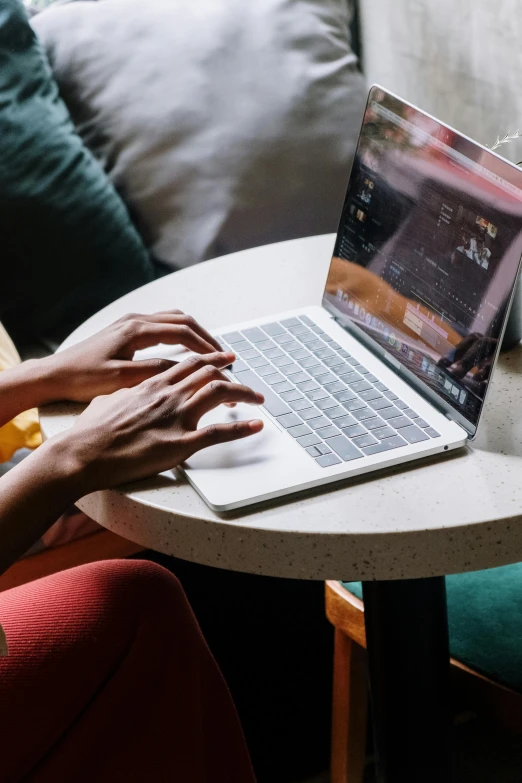 a woman sitting at a table using a laptop, by Carey Morris, pexels, happening, bottom angle, sitting in a lounge, thumbnail, glossy surface