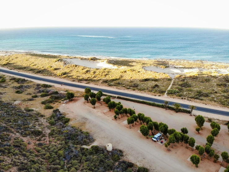 a car driving down a road next to the ocean, camp, birdseye view, desert setting, views to the ocean