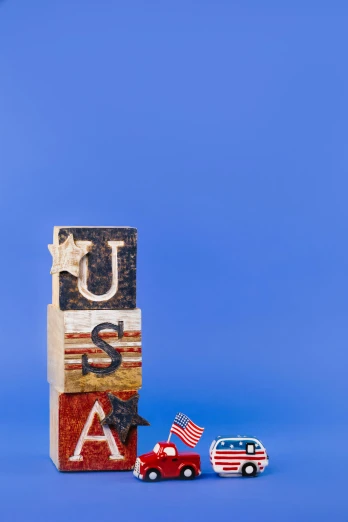 a toy truck sitting next to a block with the word usa written on it, by Alison Geissler, american realism, full frame image, statues, stacked image, military flags