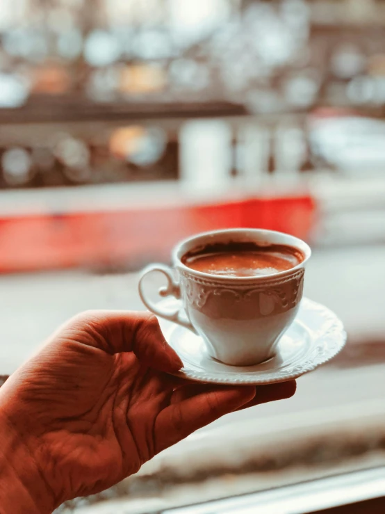 a person holding a cup of coffee in front of a window, by Lucia Peka, pexels contest winner, hurufiyya, mixture turkish and russian, 15081959 21121991 01012000 4k, drinking coffee at central perk, thumbnail