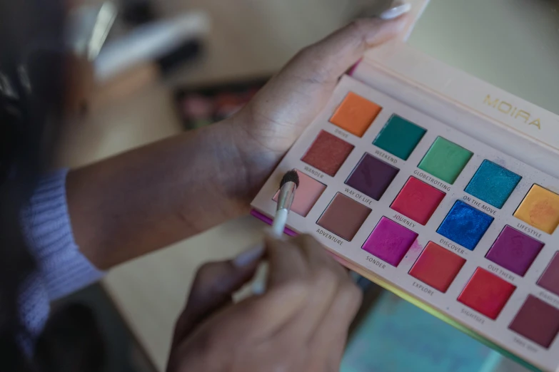 a close up of a person holding a palette, wearing eye shadow, curated collections, multicoloured, item