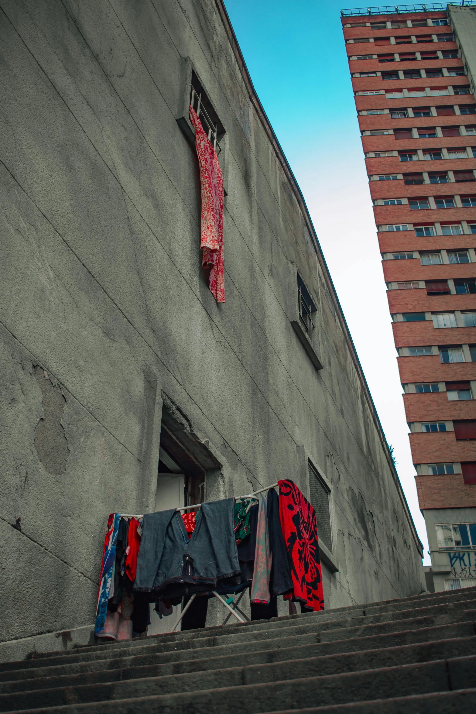 clothes hanging on a clothes line in front of a building, by Daarken, street art, red torn fabric, soviet style cyberpunk, street photo, color photo